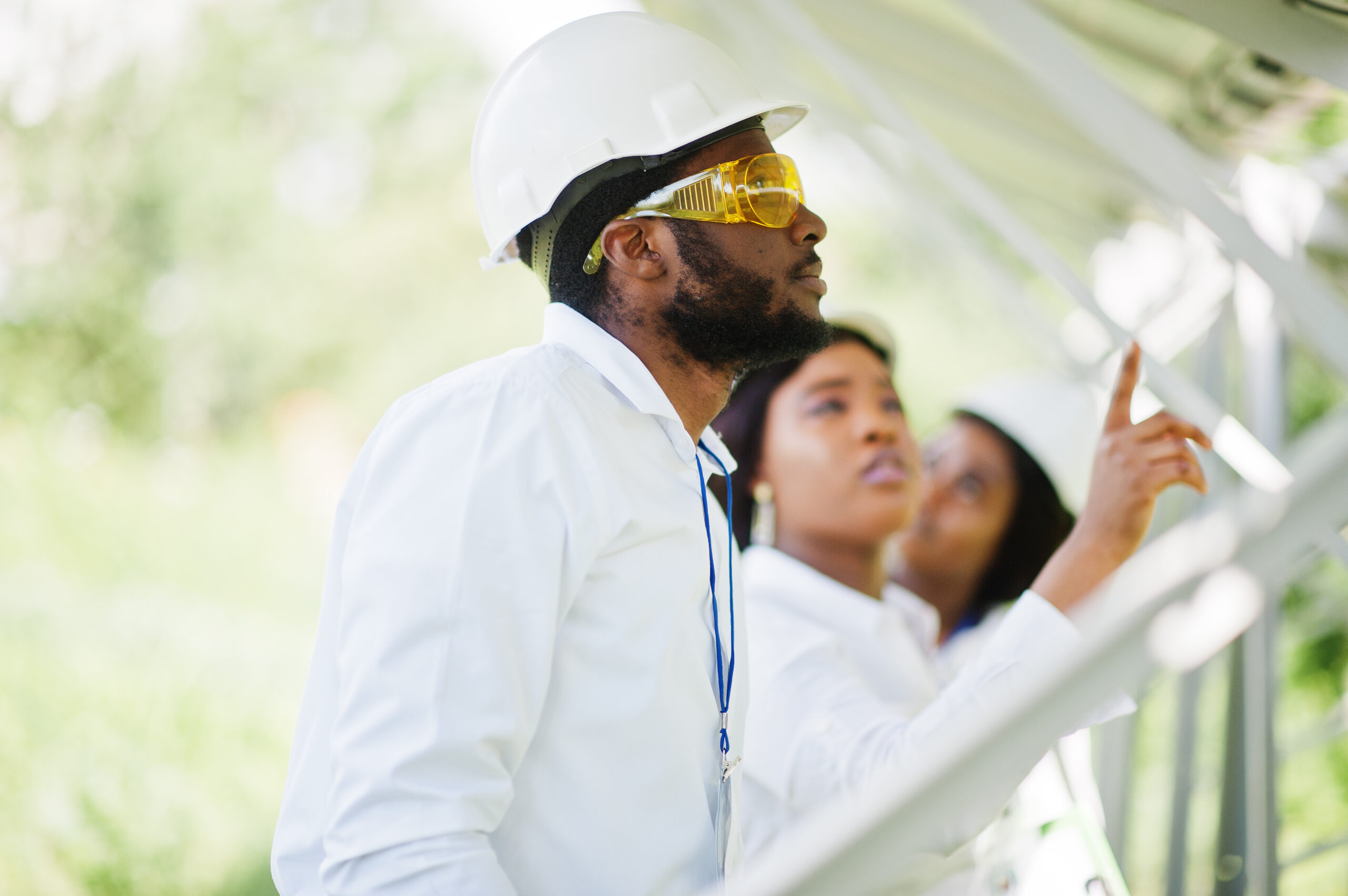 African american technician checks the maintenance of the solar panels. Group of three black engineers meeting at solar station.